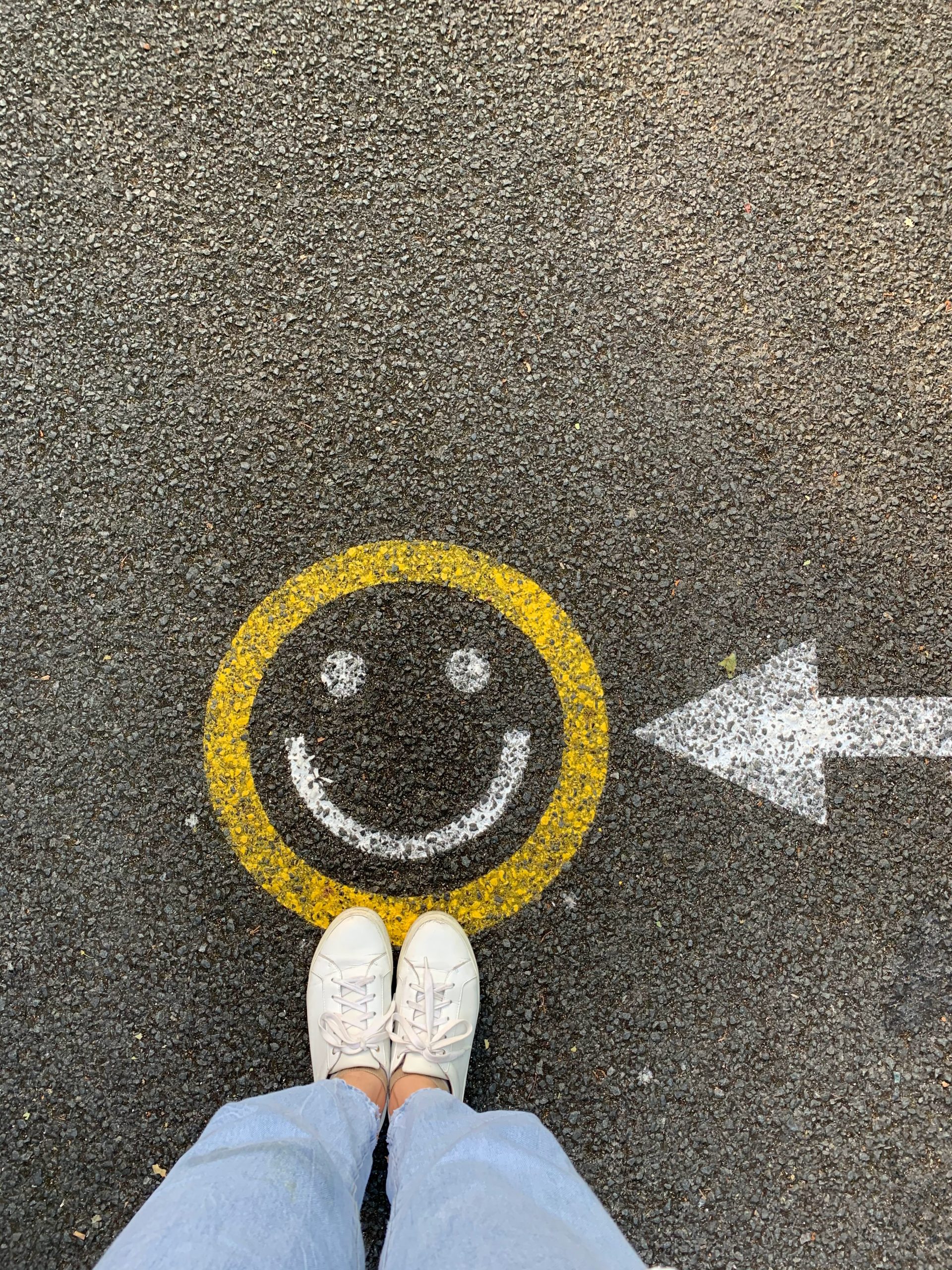 Woman With White Tennis Shoes On Concrete With Smiley Face