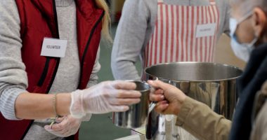 Woa=man And Man Serving Soup To Elderly Woman Wearing Mask