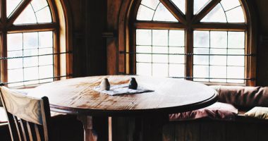 Brown Wooden Chairs Around Wood Table Alongside Arched Windows