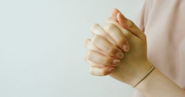 Person Wearing Pink Crewneck T-shirt While Clasping Hands