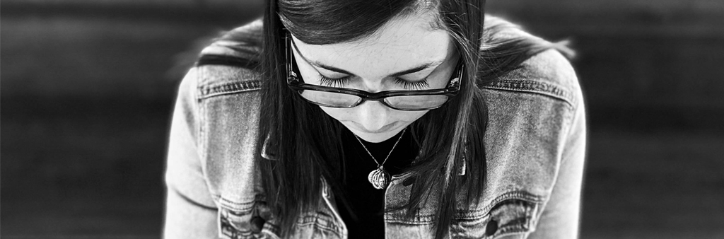 Black And White Photo Of Girl With Black Glasses Looking Down